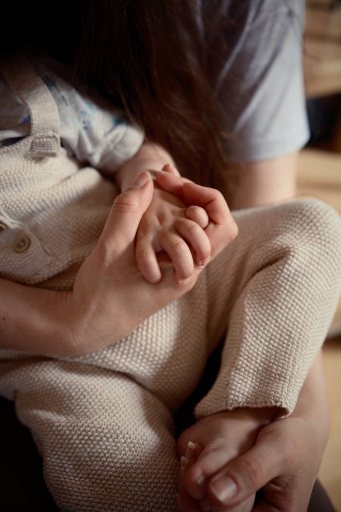 A tender moment of a mother holding her baby's hand, symbolizing love.
